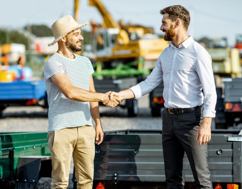 Two white men shaking hands over an equipment deal through a chattel mortgage