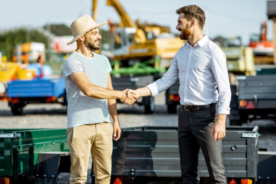 Two white men shaking hands over an equipment deal through a chattel mortgage