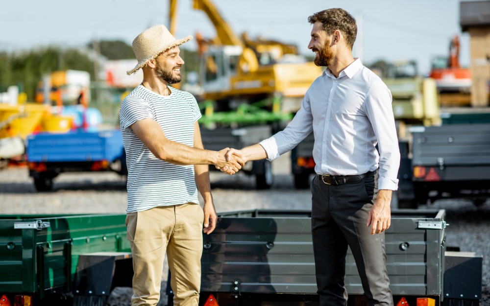 Two white men shaking hands over an equipment deal through a chattel mortgage